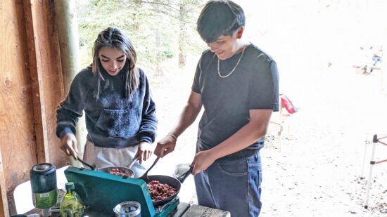 Two students cooking on a camp stove at their Cheley overnight.