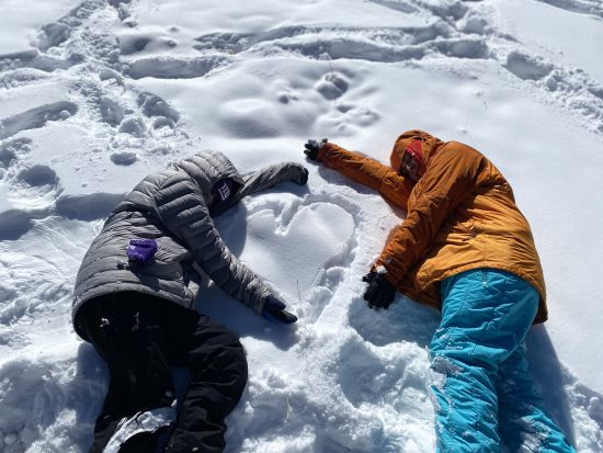 Two students in the snow with a heart
