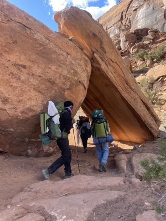 Peak to Peak students walk under huge fallen boulders on their backpacking trip through Dominguez Canyon.