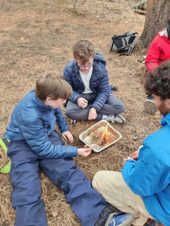 Angevine students get help from Instructor David while building a fire at Cheley Outpost.