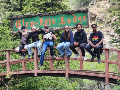 Longmont Youth Center students sit on a bridge in front of the Glen-Isle Lodge sign on the overnight trip.