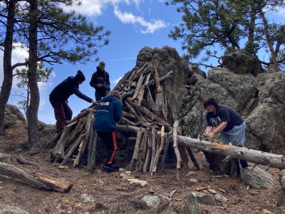 NVHS students build a shelter with found materials during a break from the rain-snow mix that had been falling.