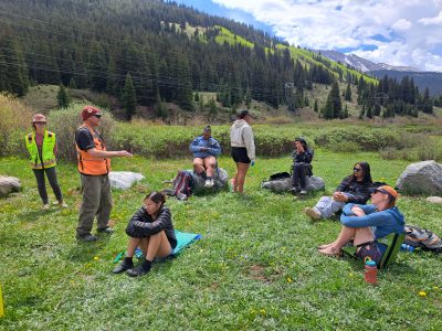 RiseUp students sit outdoors in a shot with a mountain view on their trip focused on learning about Colorado's water.