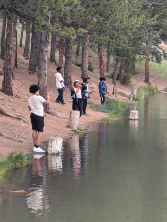 Students space themselves out along the shore while practicing fishing.
