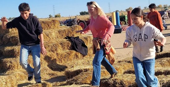 LEO program participants run around on and around some hay bales during their harvesting day at Miller Farms.