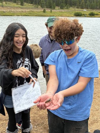 An AXL student holds a crayfish that they found at a pond at Golden Gate Canyon State Park.