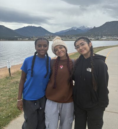 Three AXL students pose near Estes Park with the mountains in the background.
