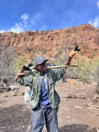 A Changemaker pauses outdoor service work to post in front of steep cliffs. Our top 10 ways to make a difference will support our Changemaker programs.